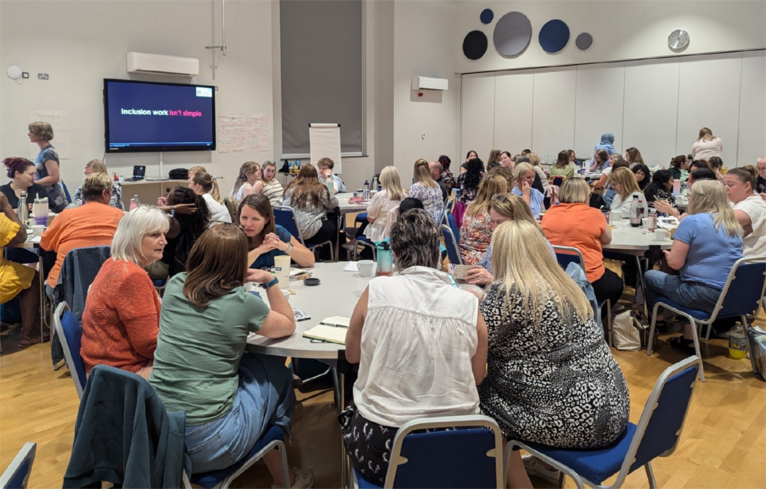 Large groups of people collaborating around tables at a co-creation event